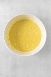 a bowl of yellow liquid on a white surface.