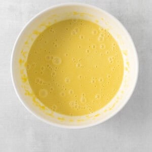 a bowl of yellow liquid on a white surface.