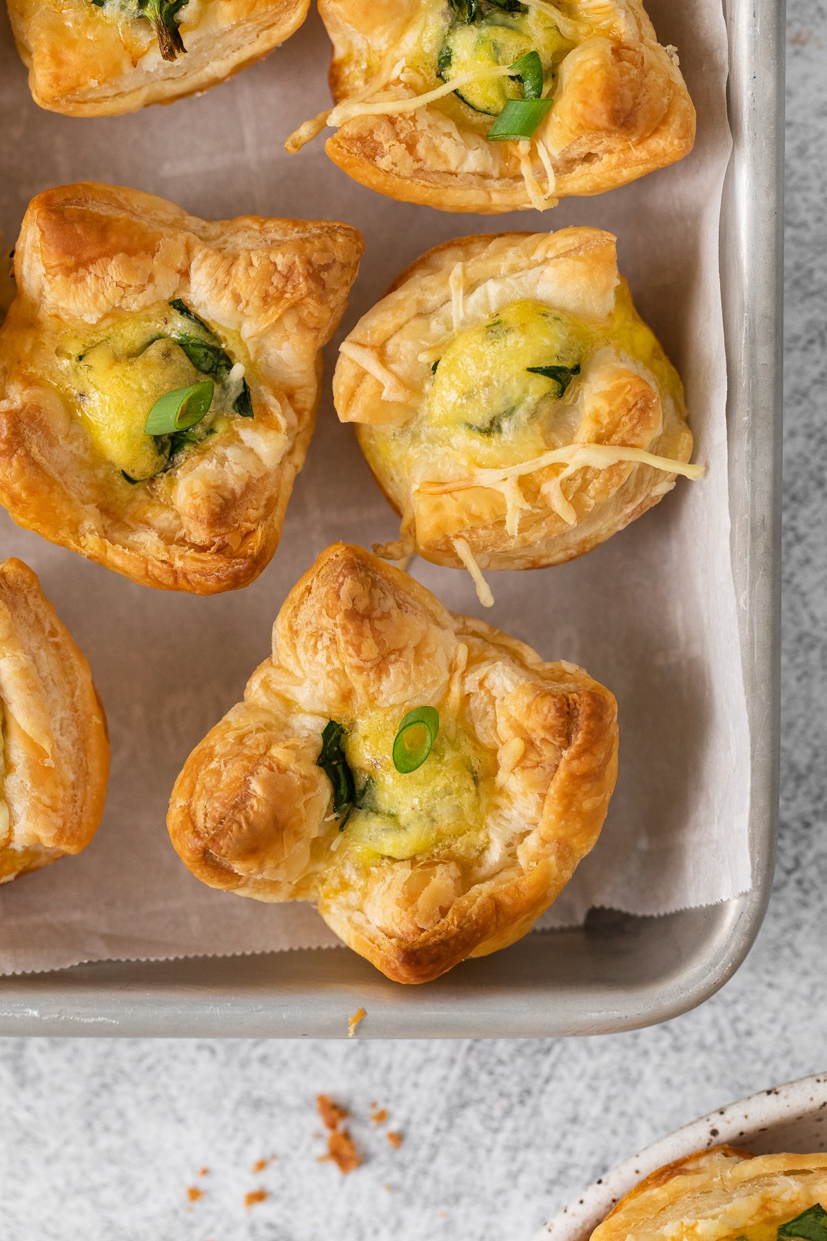 Mini quiche florentine on a baking tray.