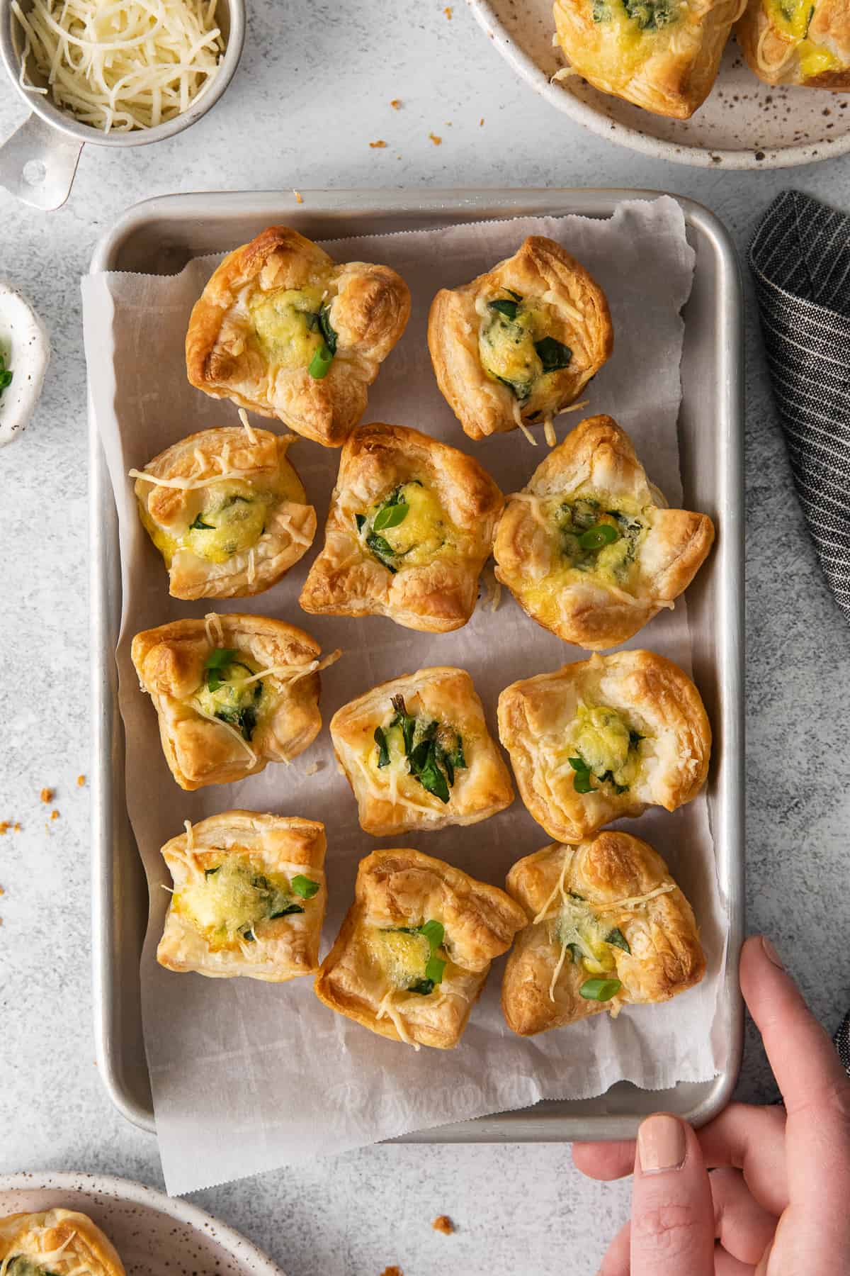 Mini quiche florentines on a baking tray with parchment paper.