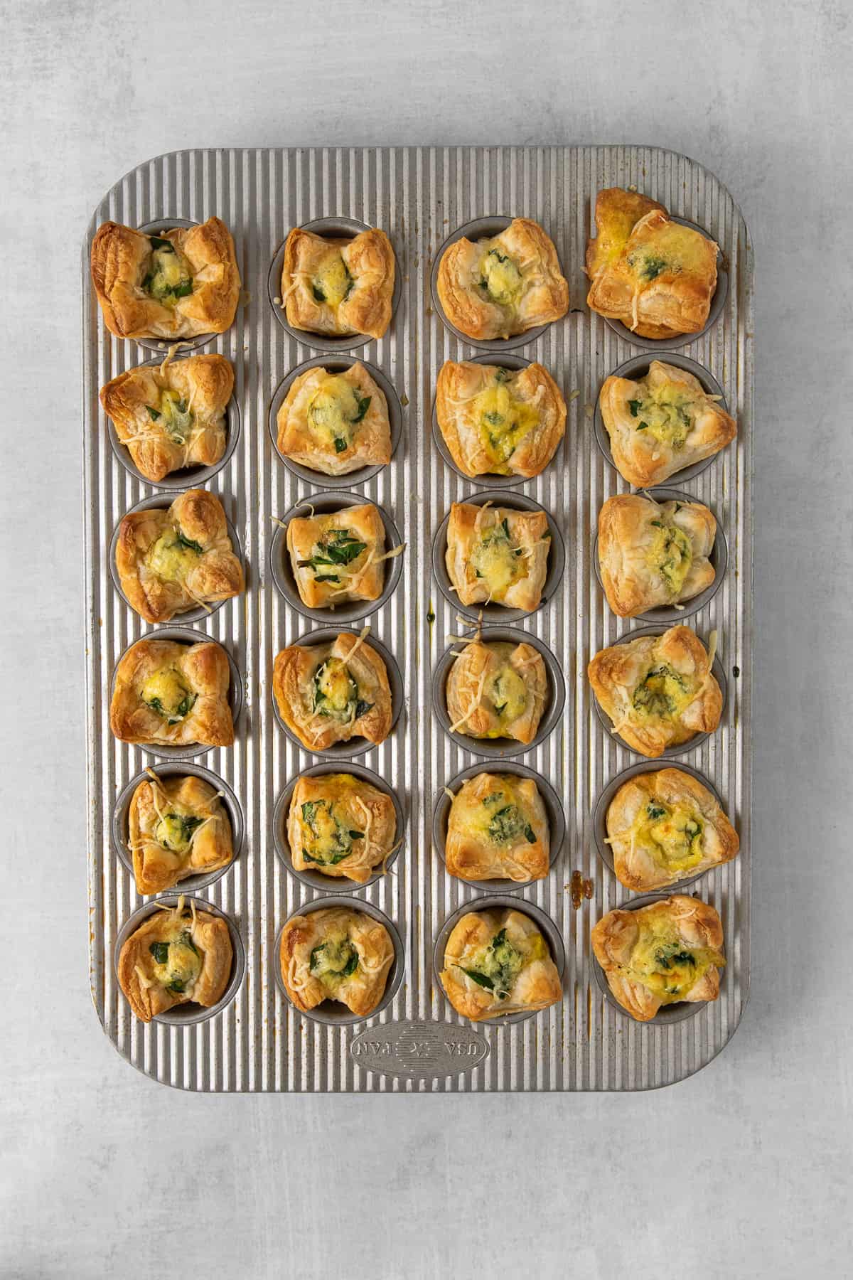 Mini quiche florentine in cooked in a mini muffin tin.