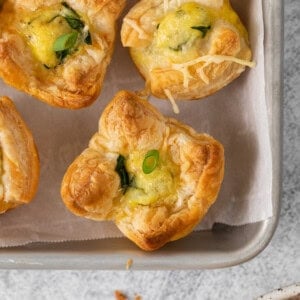 Mini quiche florentine on a baking tray.