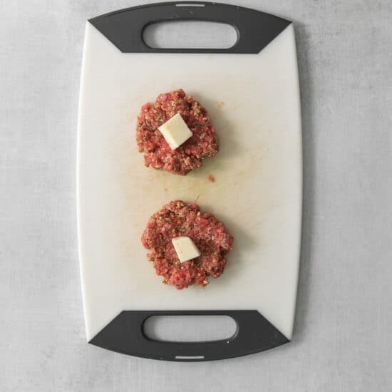 two meatballs on a cutting board.
