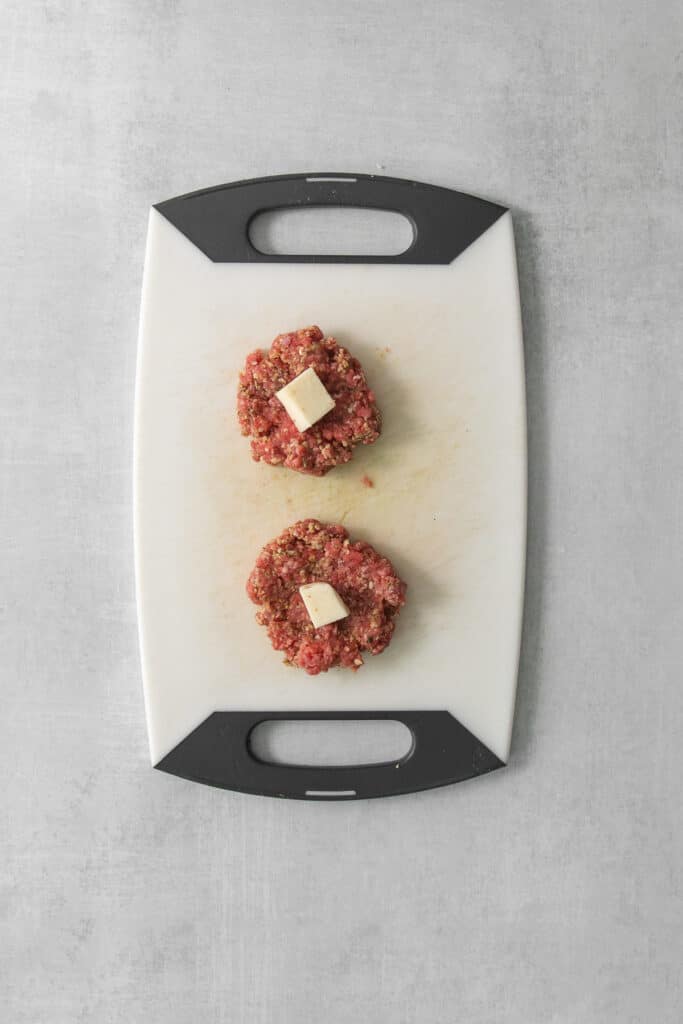 two meatballs on a cutting board.