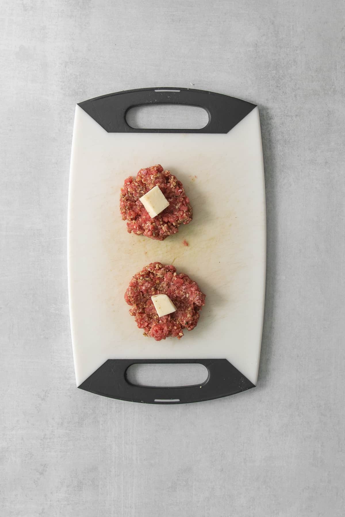 two meatballs on a cutting board.