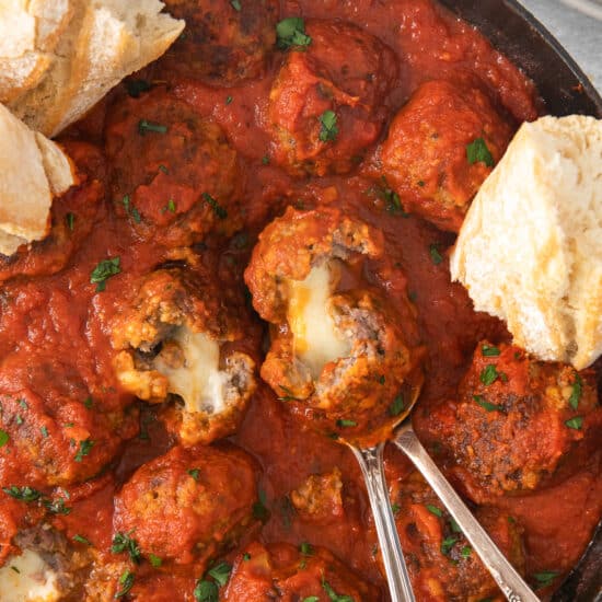 meatballs in a skillet with bread and sauce.