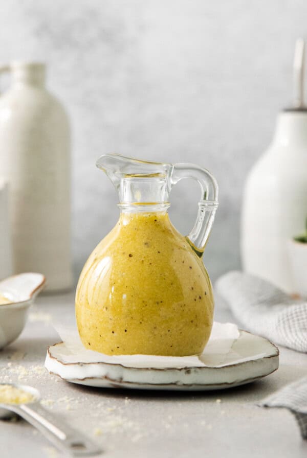 a glass jug of mustard sitting on top of a plate.