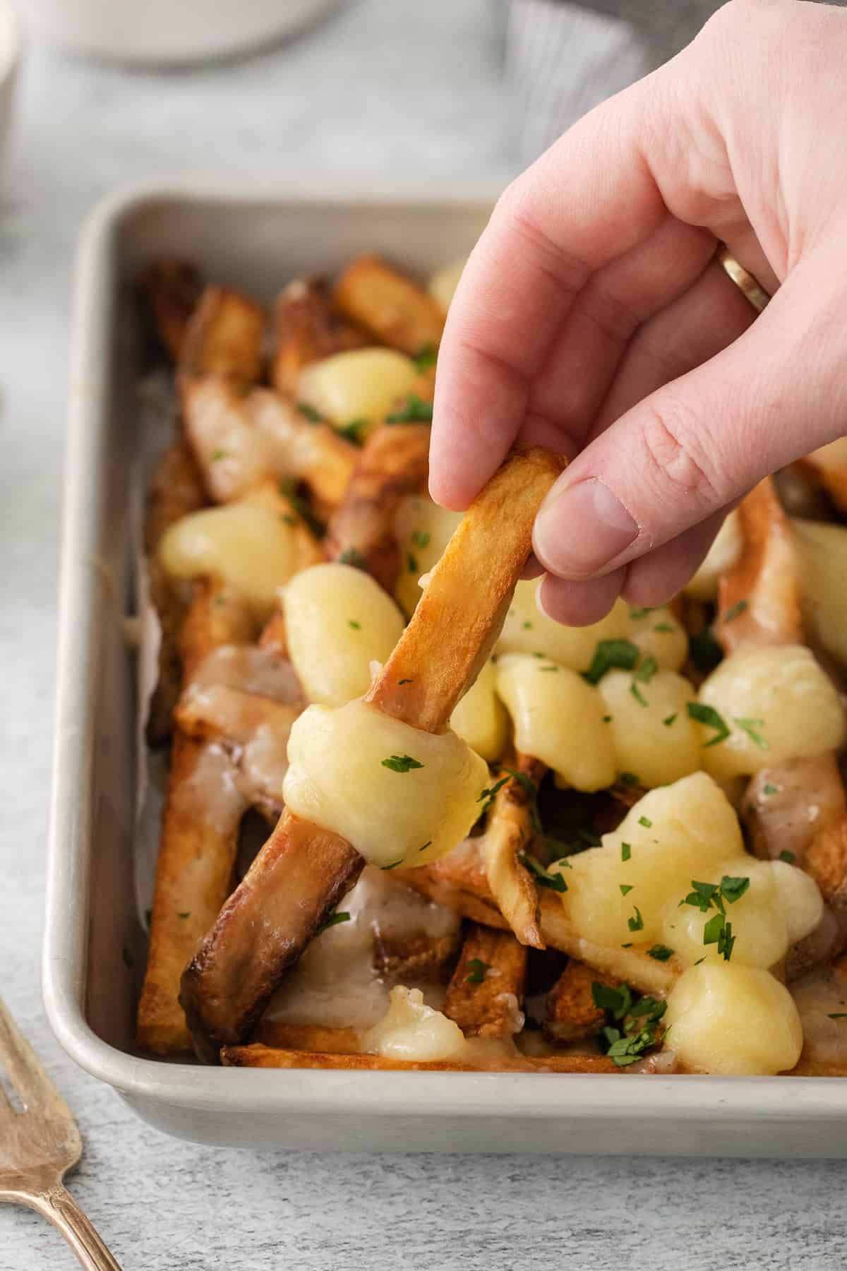 a person dipping a piece of bread into a casserole.