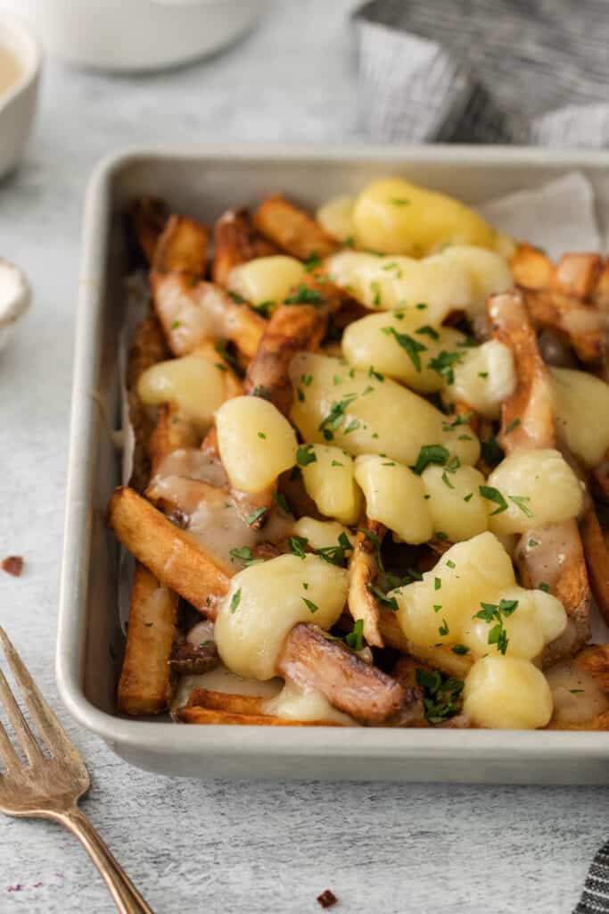 a white dish filled with potatoes and meat.