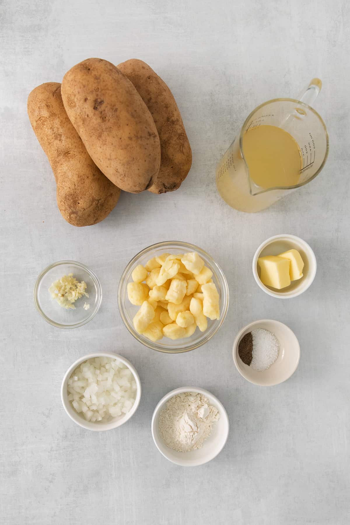 a table topped with bowls of food next to potatoes.