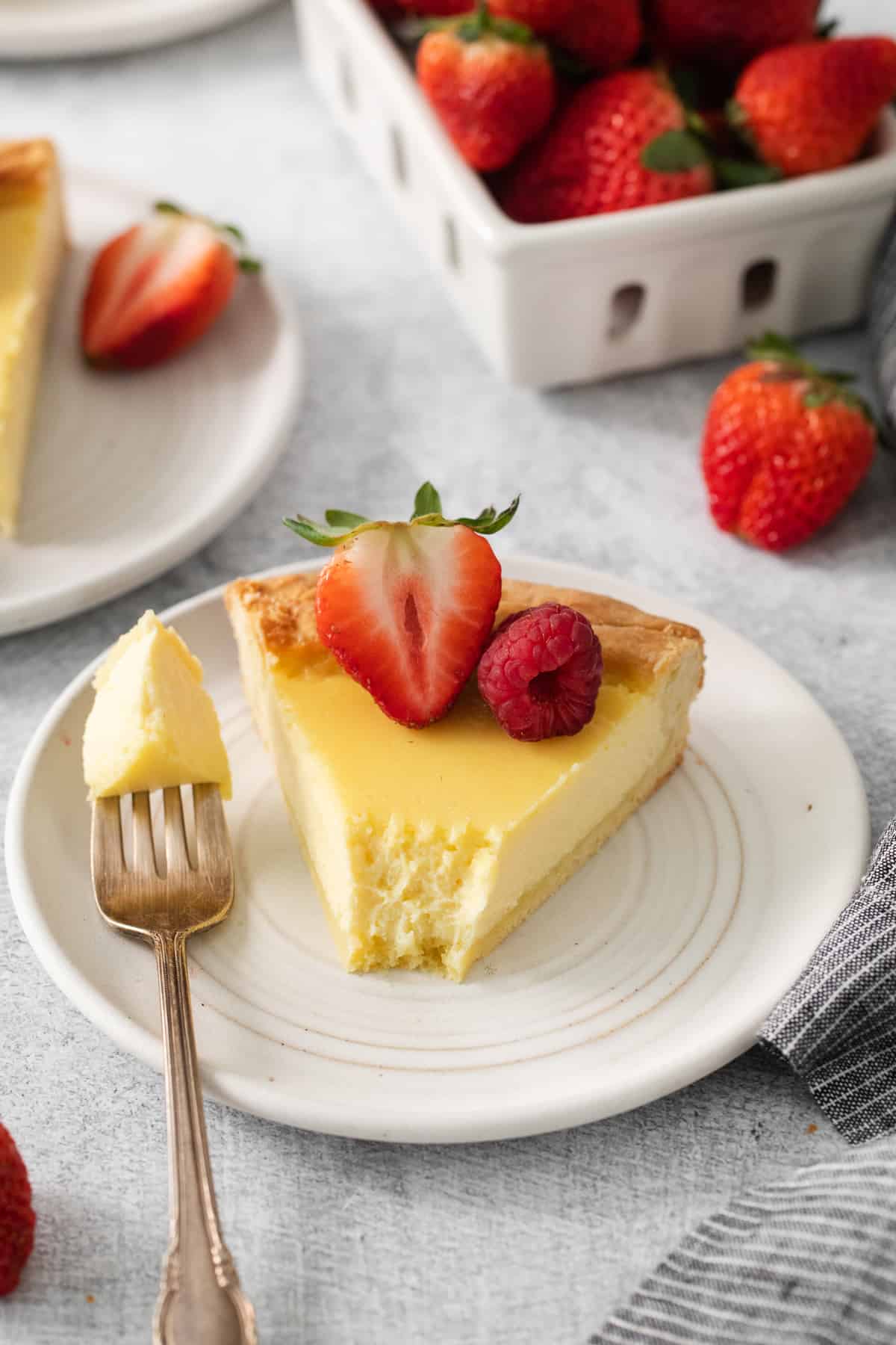This easy ricotta pie is super creamy and decadent! You'll love this simple dessert with an easy to make homemade crust. Enjoy! Slice of ricotta pie on a plate topped with sliced berries.