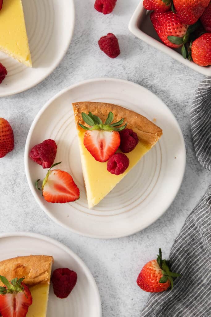 Slice of ricotta pie on a plate topped with berries.