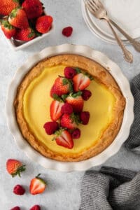 a lemon tart topped with strawberries and whipped cream.