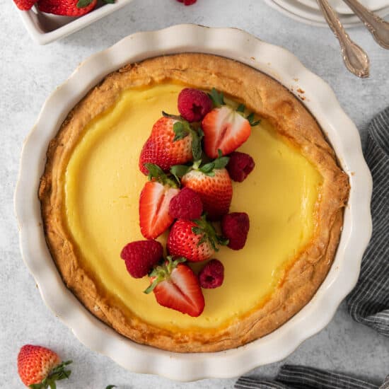 a lemon tart topped with strawberries and whipped cream.