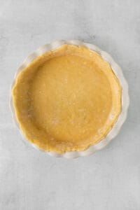 a pie crust in a white dish on a gray background.