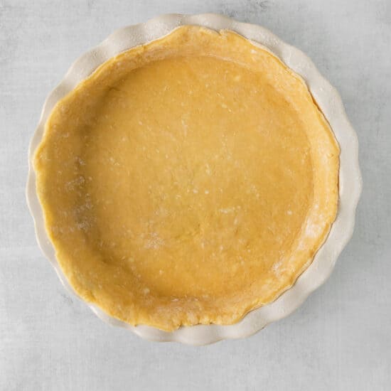 a pie crust in a white dish on a gray background.
