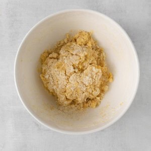 a white bowl filled with a mixture of flour and sugar.