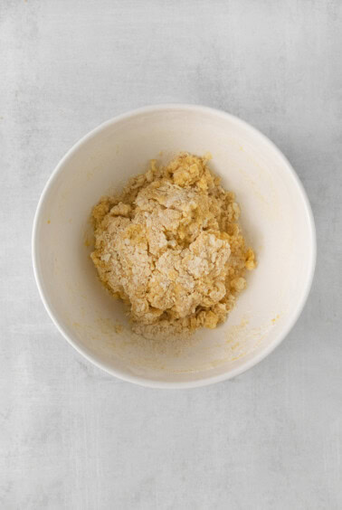 a white bowl filled with a mixture of flour and sugar.