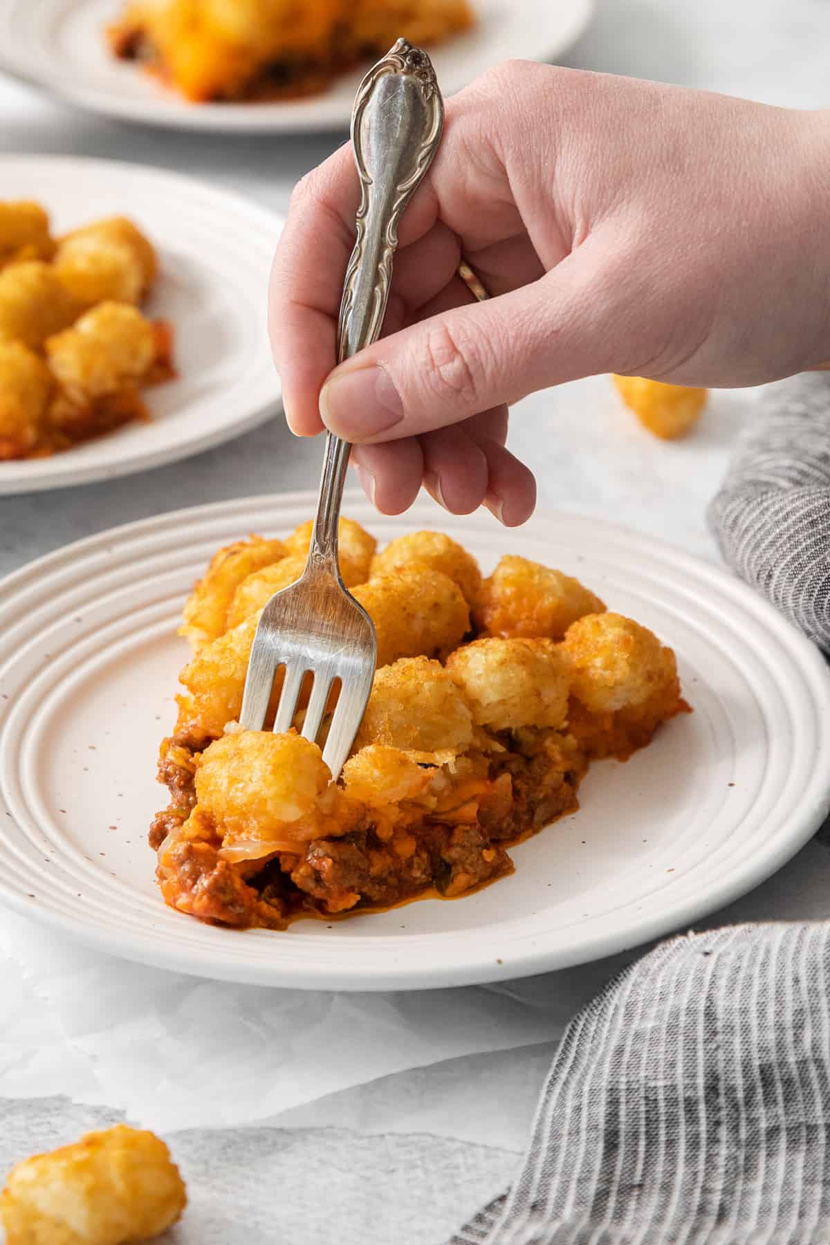 a person grabbing a piece of pizza with a fork.