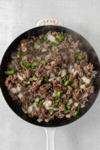 a frying pan with ground beef and onions.