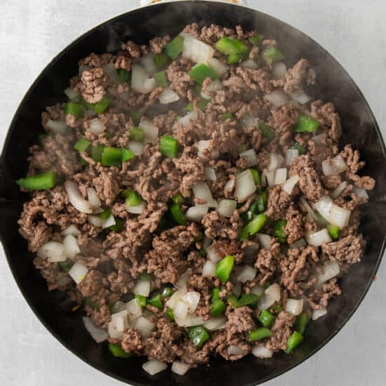 a frying pan with ground beef and onions.