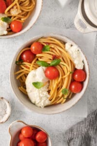 a bowl of spaghetti with tomatoes and ricotta cheese.