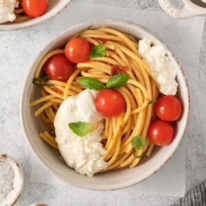 a bowl of spaghetti with tomatoes and ricotta cheese.