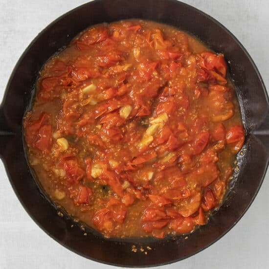 a skillet filled with tomato sauce on a table.