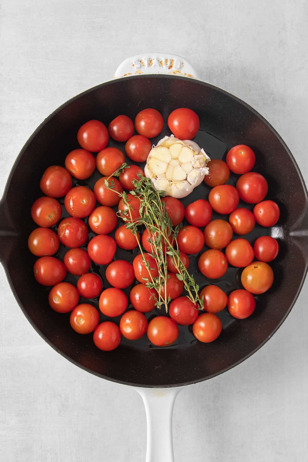 Tomatoes, garlic and fresh herbs in a cast iron skillet.