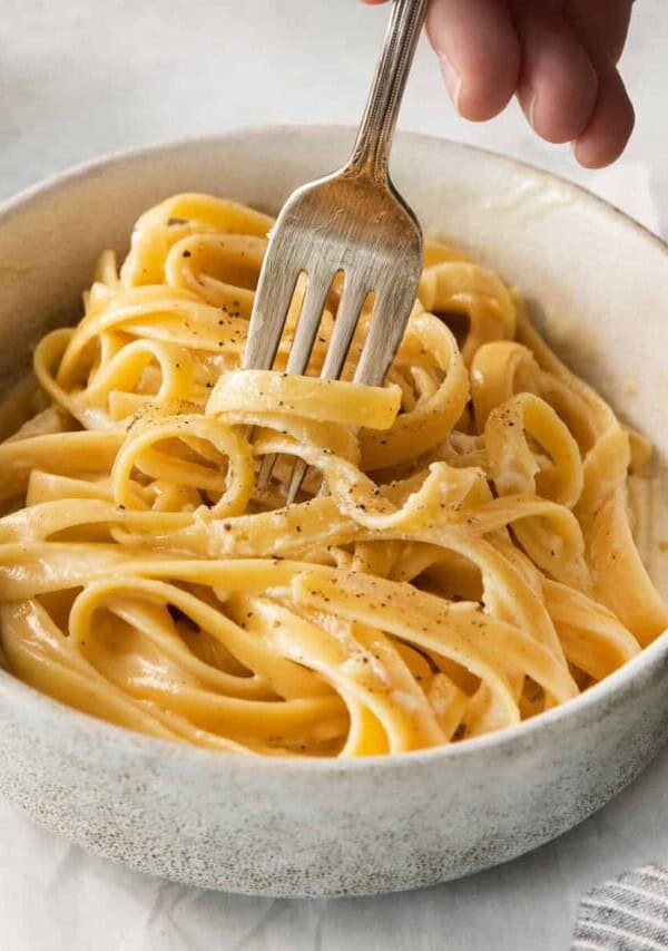 Homemade alfredo sauce over pasta in a bowl.