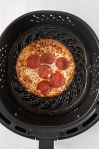 a pizza is being cooked in a black grill.