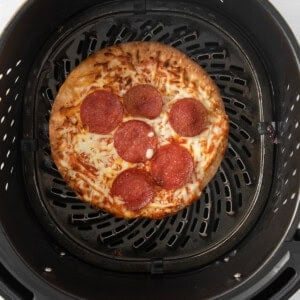 a pizza is being cooked in a black grill.