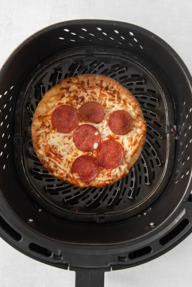 a pizza is being cooked in a black grill.