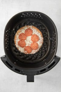 a pizza is being cooked in an air fryer.