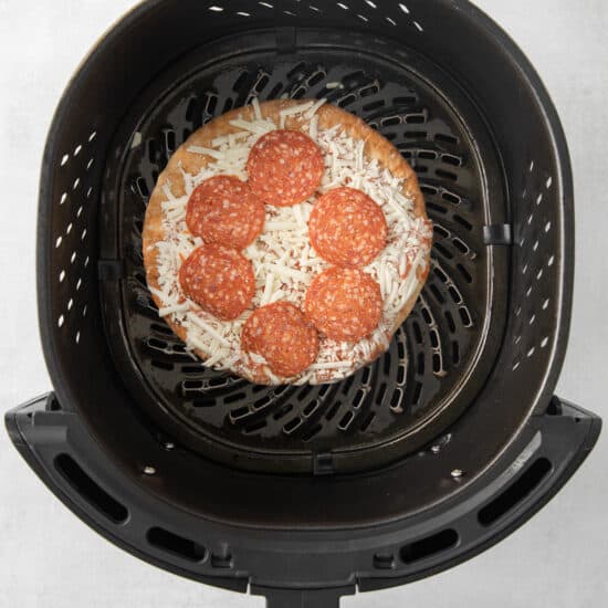 a pizza is being cooked in an air fryer.