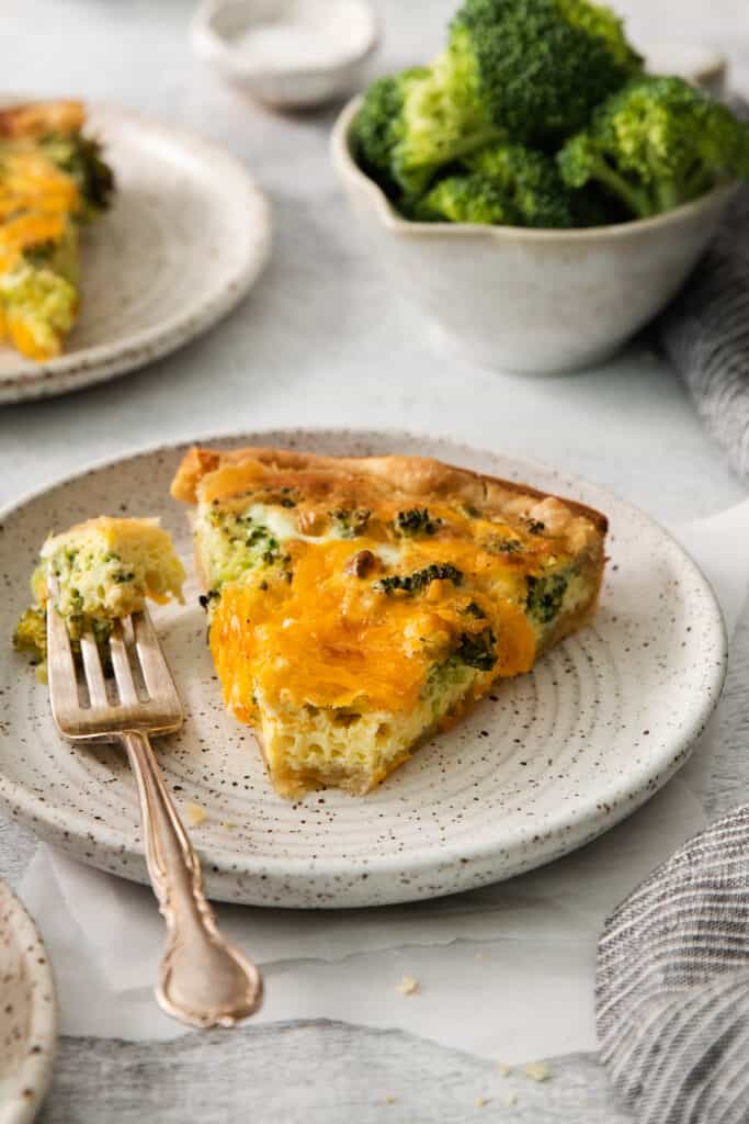 a slice of quiche on a plate with a fork.