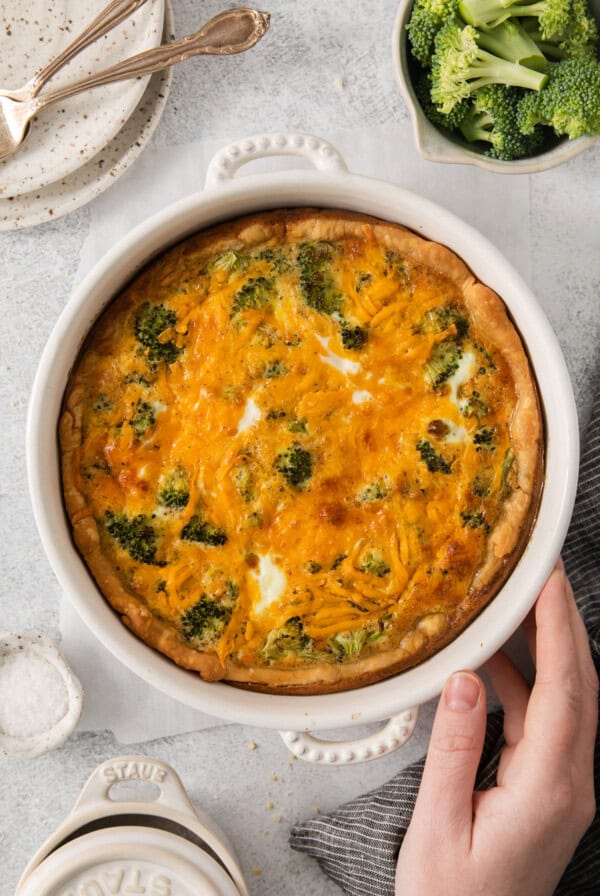 a cheesy casserole with broccoli in the background.