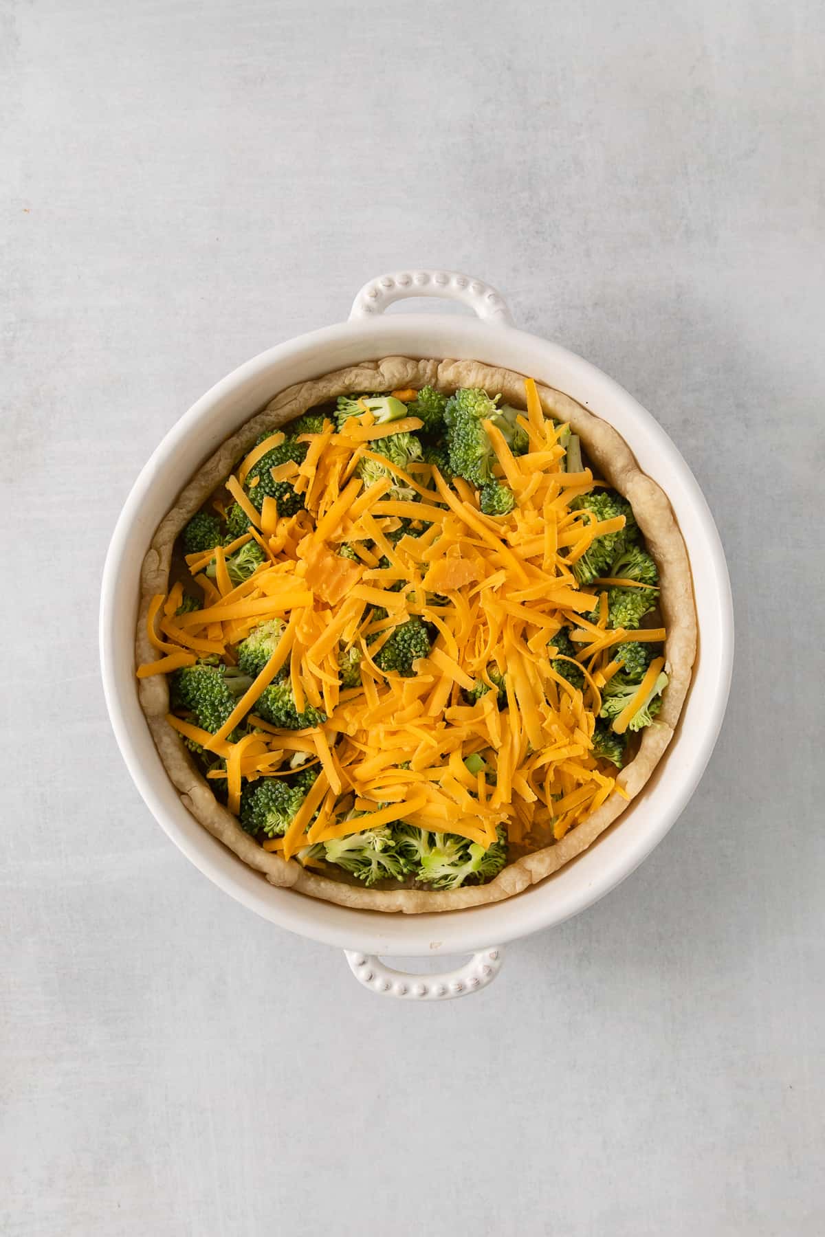 A white bowl filled with broccoli and cheese.