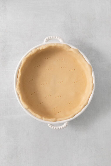 a pie crust in a white dish on a table.