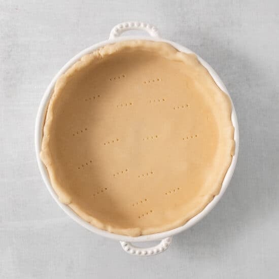 a pie crust in a white dish on a table.