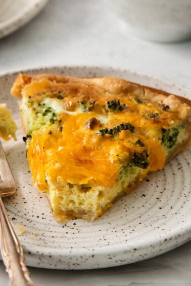 a slice of quiche on a plate with a fork.