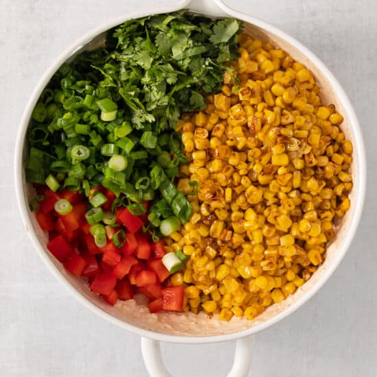 a white bowl filled with corn and vegetables.
