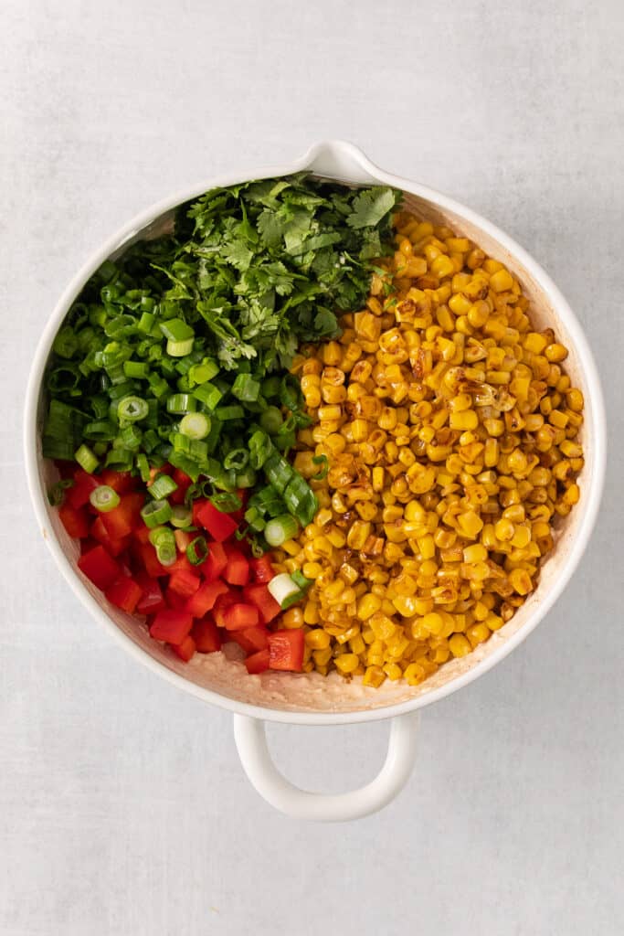 a white bowl filled with corn and vegetables.