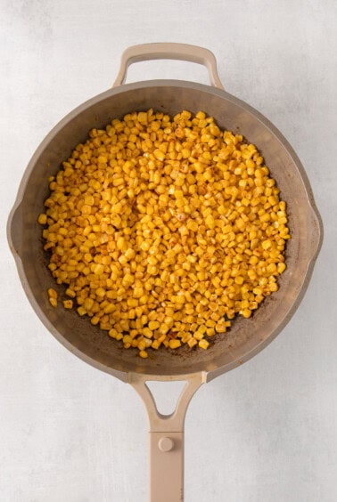 a frying pan filled with corn on top of a table.