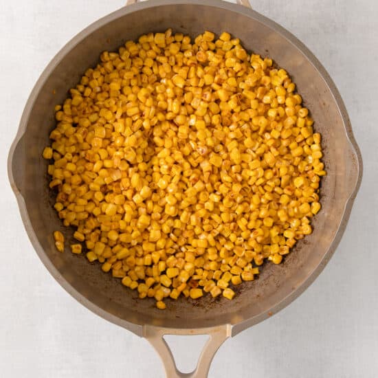a frying pan filled with corn on top of a table.