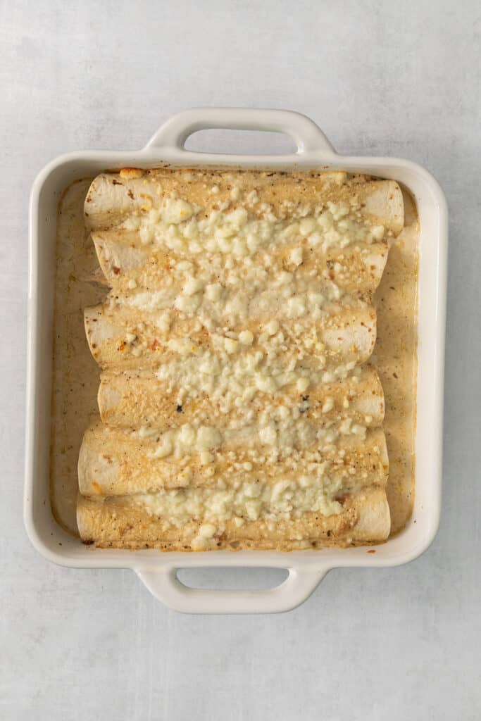 cheesy enchiladas in a white baking dish.