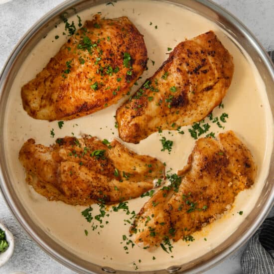 chicken breasts in a pan with mashed potatoes and broccoli.