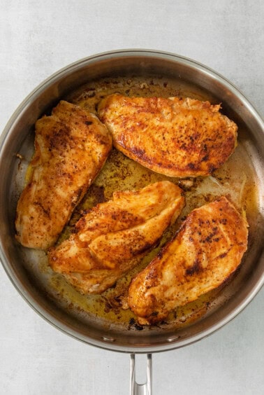 chicken breasts in a skillet on a white background.