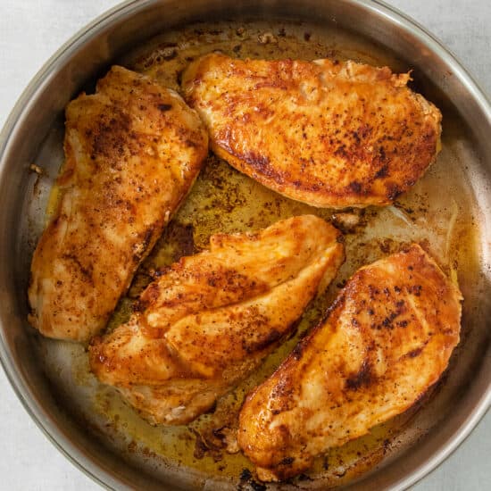 chicken breasts in a skillet on a white background.