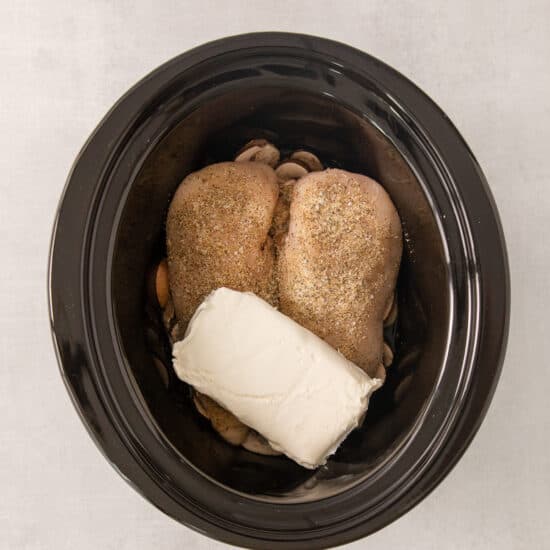 a black crock pot filled with chicken and cheese.